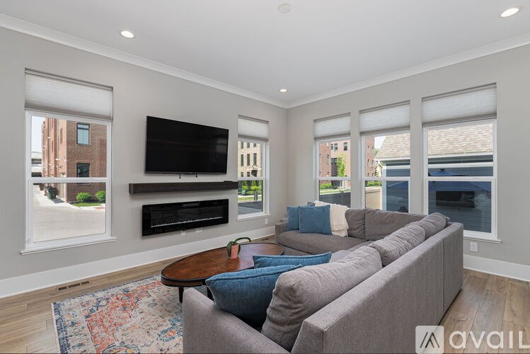 A living room with a grey couch, a wooden coffee table, and a flat screen TV mounted on the wall.