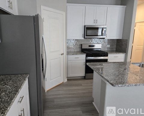 A kitchen with a black refrigerator and white cabinets.