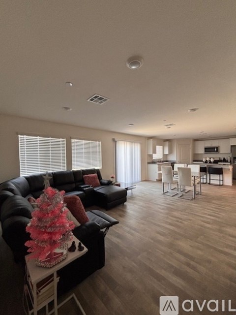 A living room with a black couch and a coffee table with a pink floral centerpiece.