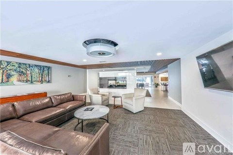 A living room with a brown leather couch and a white chair.