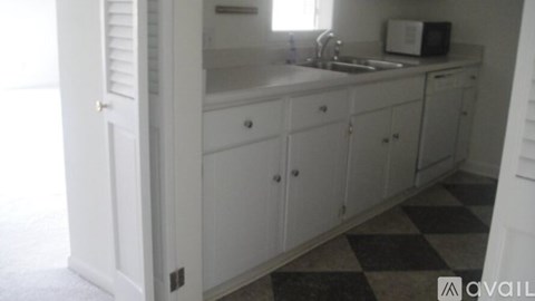 A kitchen with white cabinets and a checkered floor.