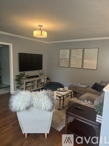 A living room with a white chair and a brown ottoman.