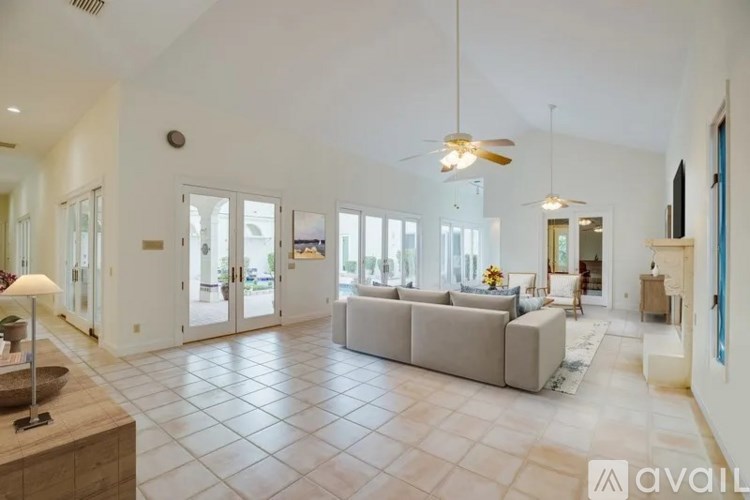 A spacious living room with a large grey sofa and a ceiling fan.