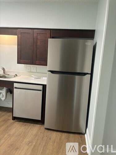 A stainless steel refrigerator stands in a kitchen next to a sink.