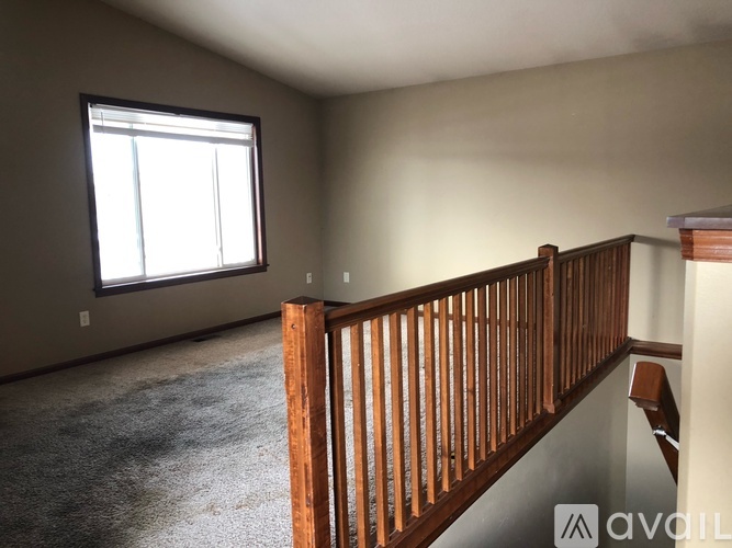 A room with a window and a wooden railing.