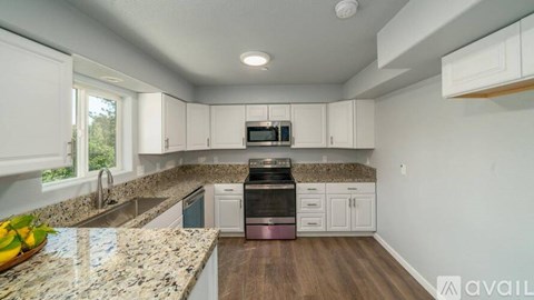 A kitchen with granite countertops and white cabinets.