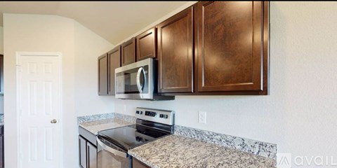 A kitchen with brown cabinets and a granite countertop.