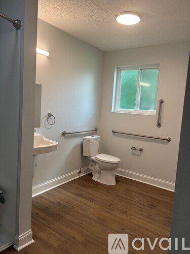 A bathroom with a toilet, sink, and window.