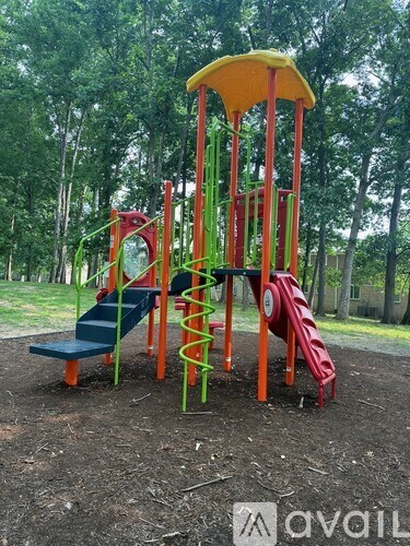 A playground with a red and green slide and a yellow canopy.