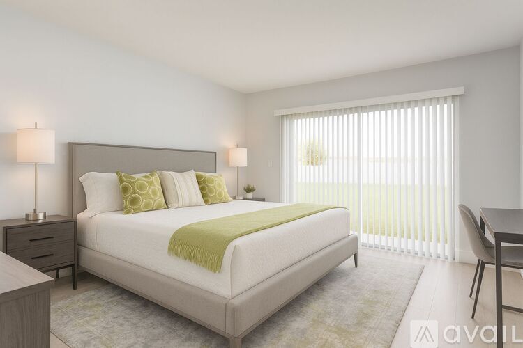 A bedroom with a large bed and a window with blinds.