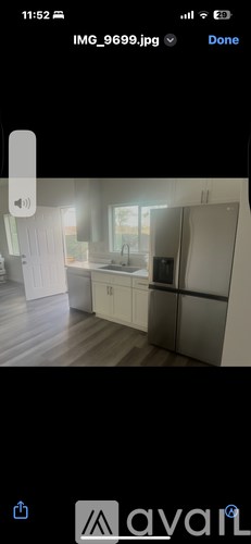 A modern kitchen with white cabinets and a wooden floor.