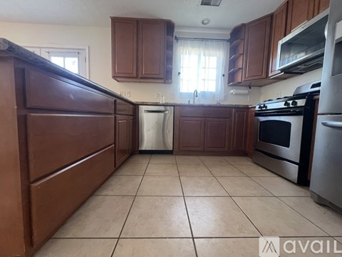 A kitchen with brown cabinets and a white dishwasher.