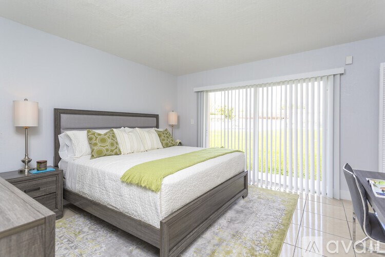 A bedroom with a large bed and a window with blinds.