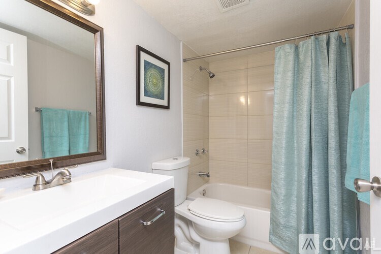 A bathroom with a white sink, toilet, and a blue shower curtain.