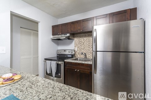A kitchen with a stainless steel refrigerator and wooden cabinets.