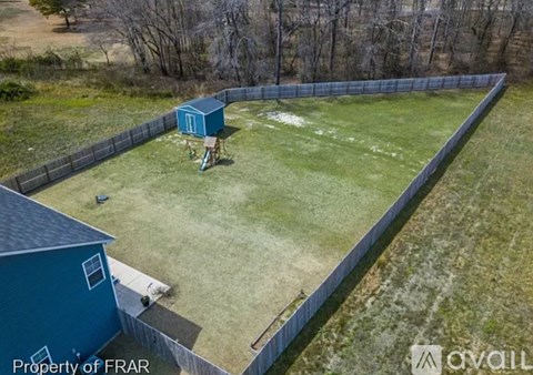 A blue shed sits in a grassy backyard.