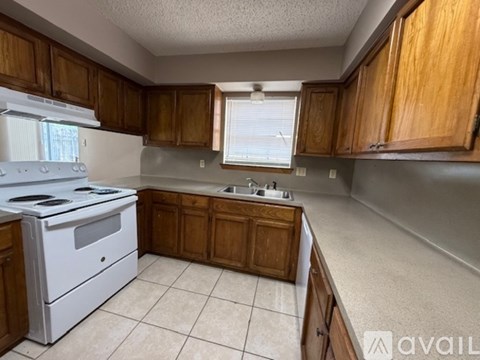A kitchen with wooden cabinets and a white stove top oven.