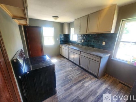 A kitchen with wooden floors and a black refrigerator.
