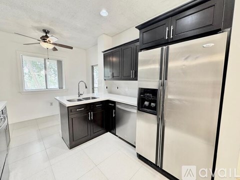 A kitchen with a stainless steel refrigerator and black cabinets.