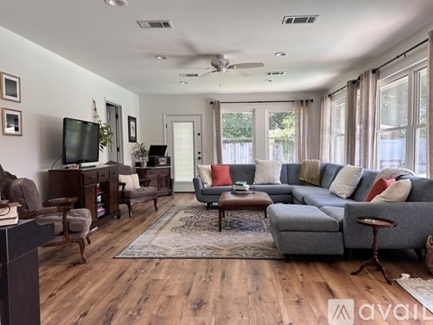 A living room with a grey sofa, a wooden coffee table, and a television on a wooden stand.