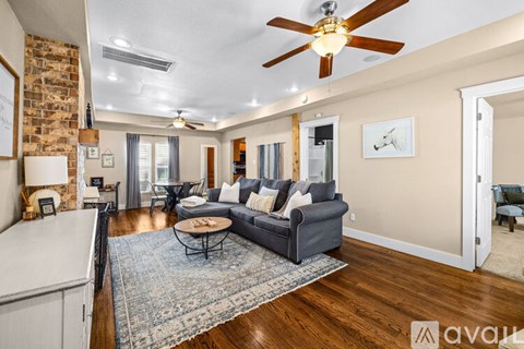 A living room with a grey couch and a ceiling fan.