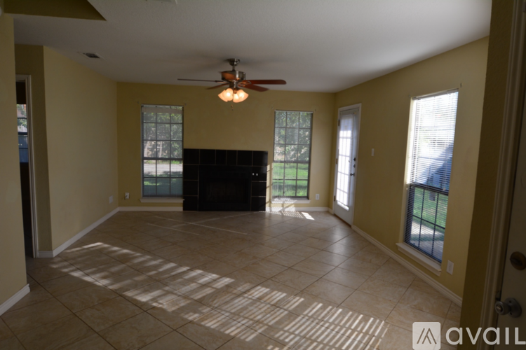 A spacious room with a ceiling fan and a large window.