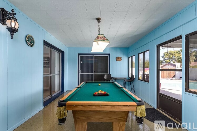A pool table with a green cloth and a television in the background.