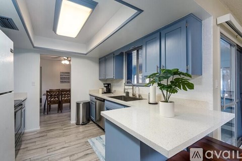 A kitchen with a white counter top and blue cabinets.