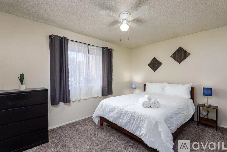 A bedroom with a bed, nightstand, and window.