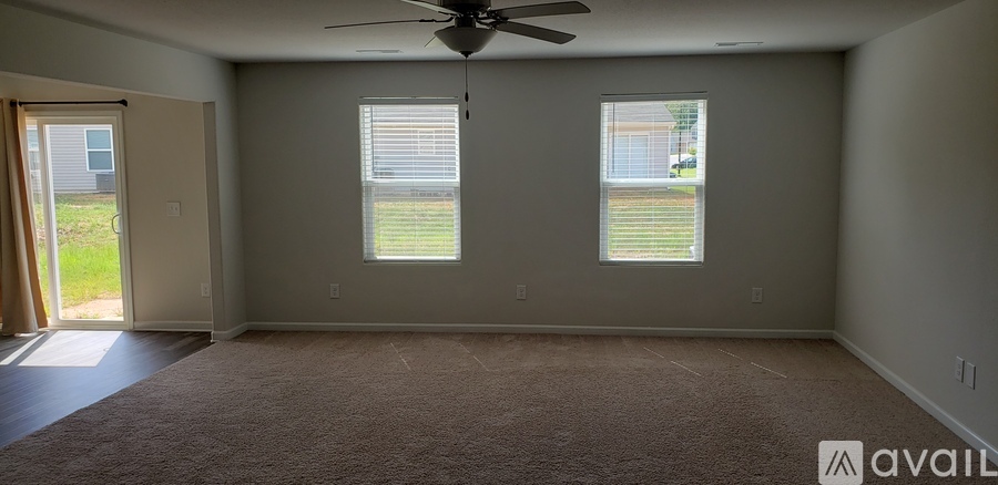 A room with a carpeted floor and a ceiling fan.