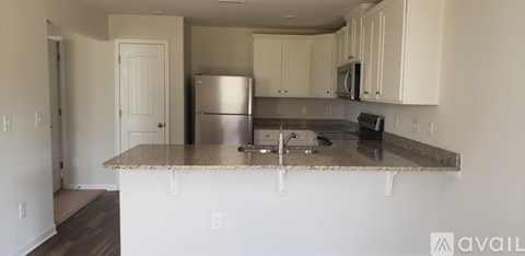A kitchen with white cabinets and a granite countertop.