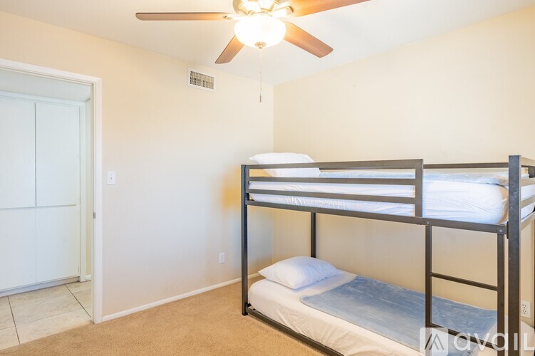 A bedroom with a bunk bed and a ceiling fan.