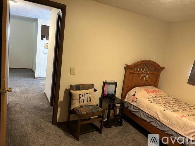 A bedroom with a bed, chair, and a pillow with the word "FAITH" on it.