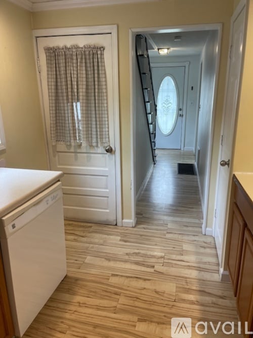 A white dishwasher is in a kitchen with wood flooring.