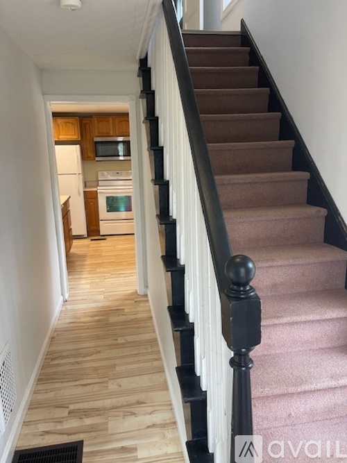 A staircase with a black railing and pink carpet.