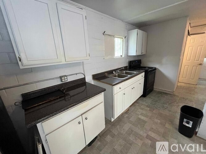 A kitchen with white cabinets and a black countertop.