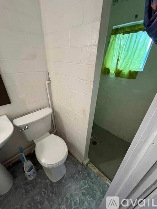A white toilet with a blue toilet brush in a bathroom.