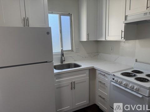 A kitchen with white cabinets and a white stove top oven.