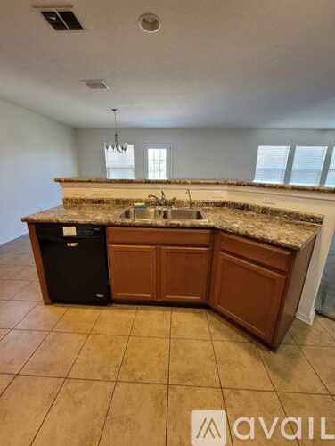 A kitchen with a black trash can and a sink under a window.
