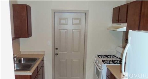 A small kitchen with a white door, a stove, and a sink.