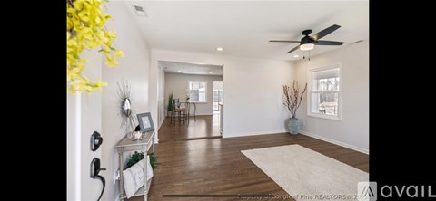 A spacious living room with a white rug and a ceiling fan.