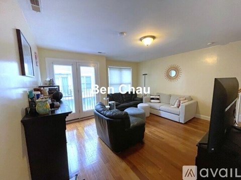 A living room with a black leather couch and a white sofa.