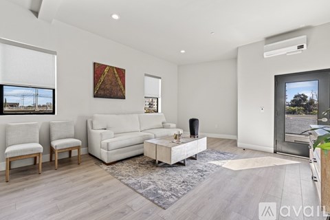 A living room with a white sofa, two chairs, a coffee table, and a painting on the wall.