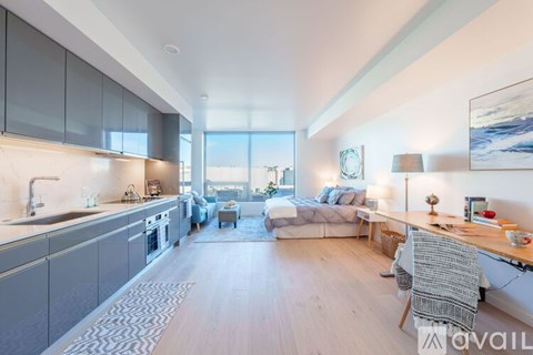 A modern kitchen with a dining area and a living room with a couch and a chair.