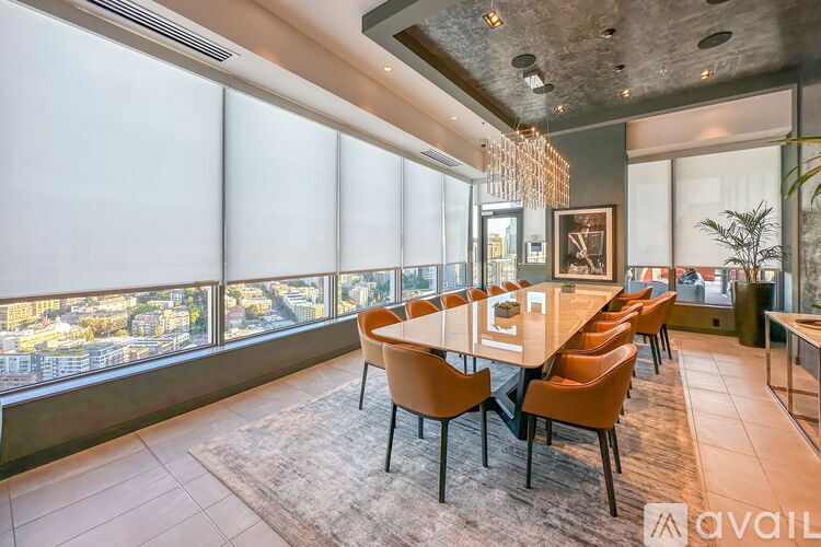 A dining room with a long table and chairs with a view of the city.