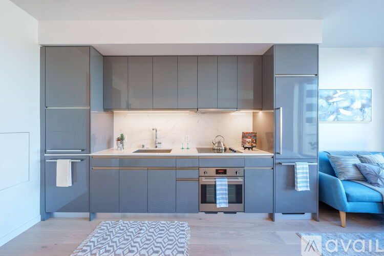 A modern kitchen with a blue couch and a patterned rug.