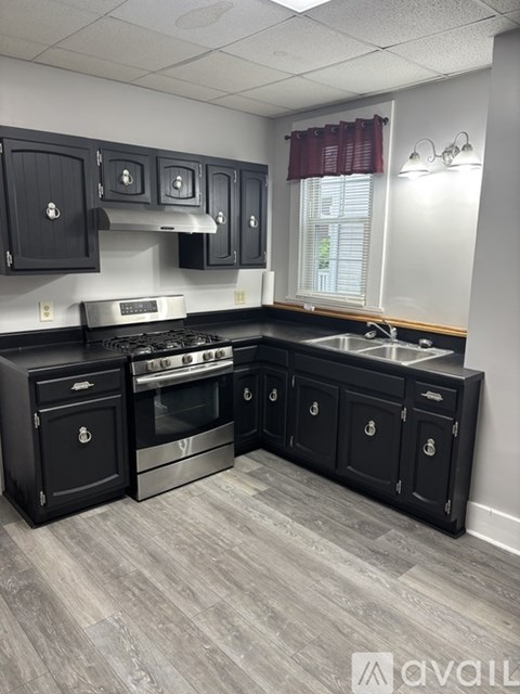 A kitchen with black cabinets and a stove top oven.