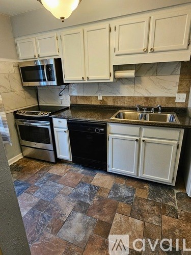 A kitchen with black appliances and white cabinets.