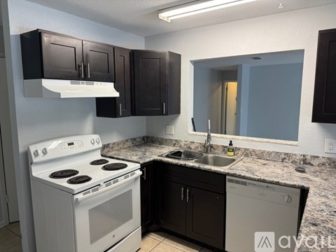 A kitchen with a white stove and black cabinets.