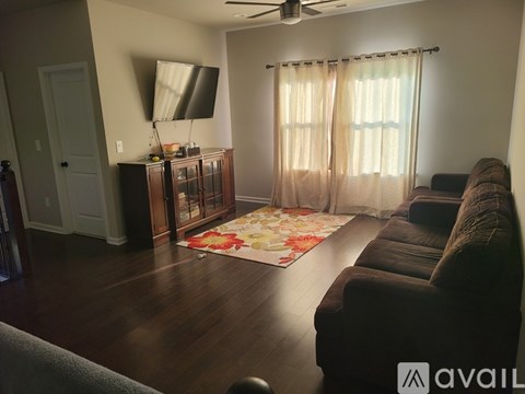 A living room with a brown couch and a television on a cabinet.